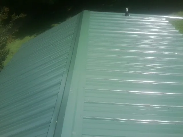 New green metal panels meeting at the ridge of a roof — Flat Roof Repair work by our crew in Bremo Bluff
