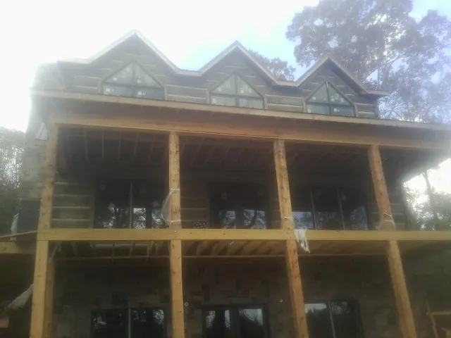 Dormers and porch framing on a large log home under construction — Roof Coating work by our crew in Bremo Bluff