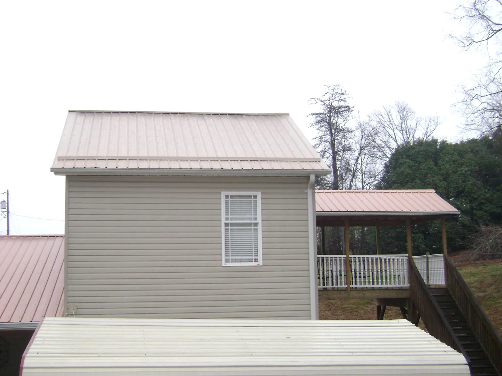 Tan metal roofs on a two story addition and attached porch, from a Roof Replacement job in Bremo Bluff