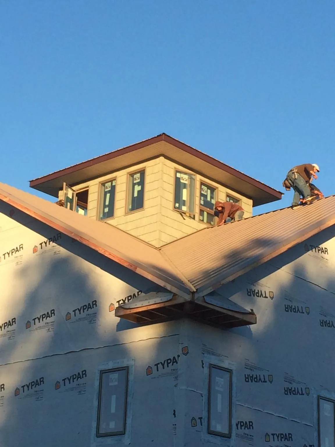 Roofers working around a rooftop cupola on a new metal roof at sunset — Roof Waterproofing in Bremo Bluff by Roofing Brothers